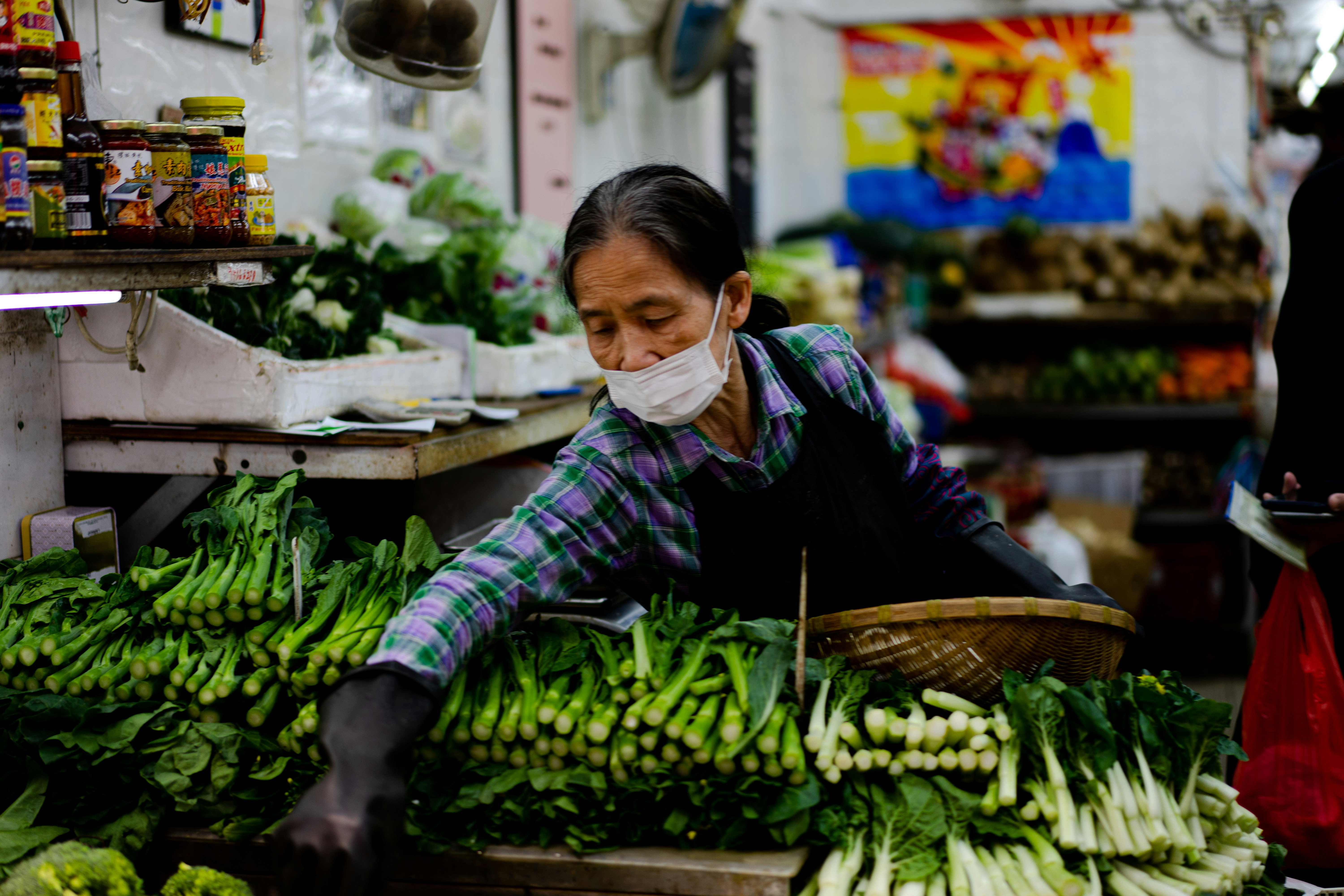 woman in black jacket holding green vegetable